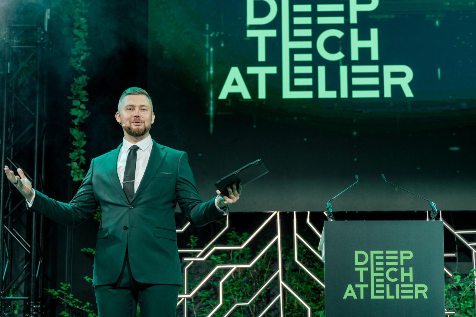 Prezentētājs uz skatuves ar uzrakstu “Deep Tech Atelier”