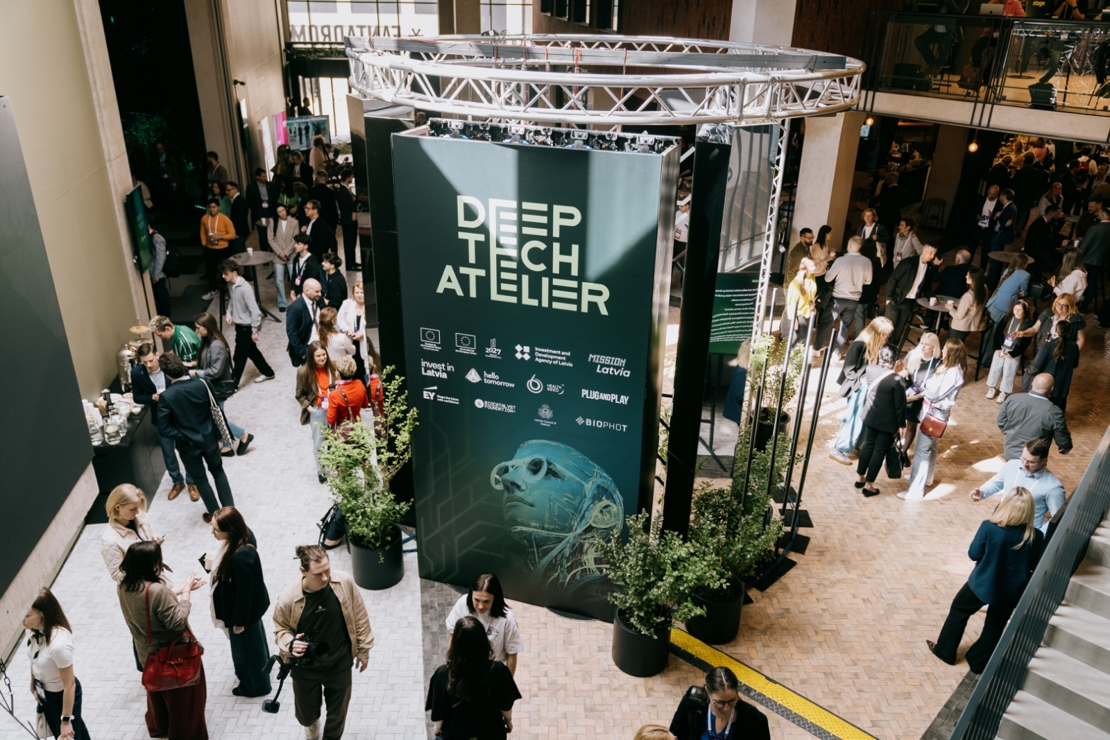 Plašs skats uz “Deep Tech Atelier” pasākuma telpu ar lielu centrālo stendu
