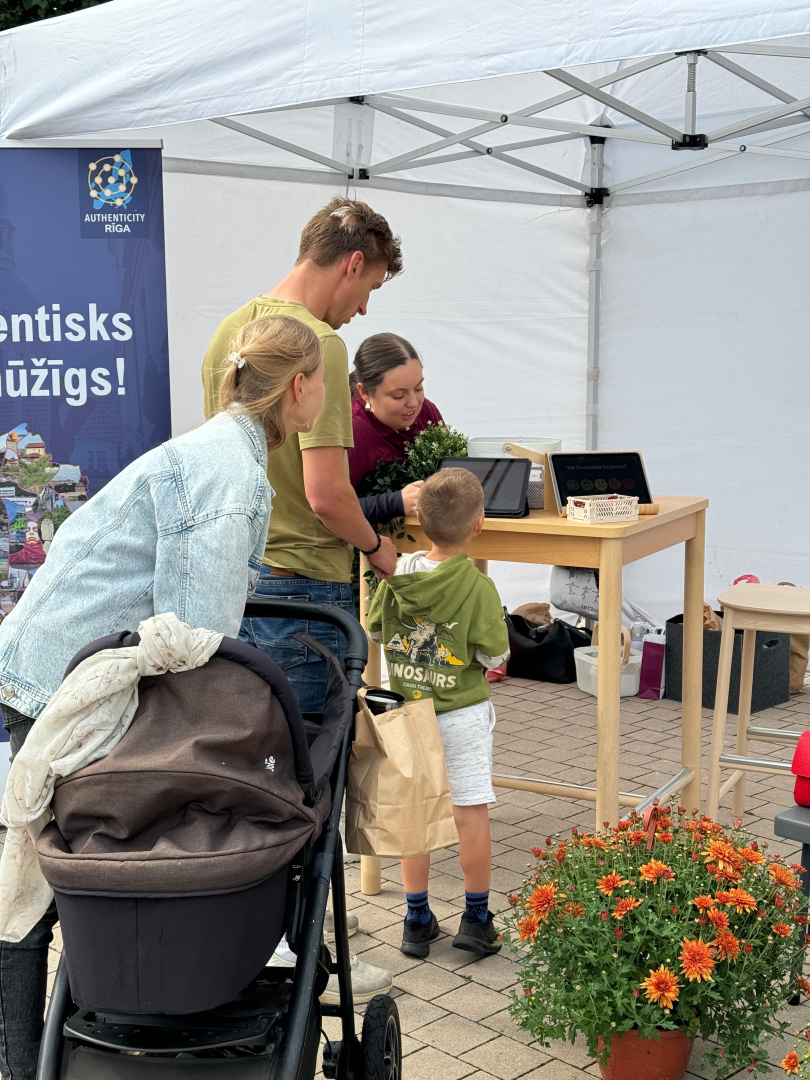 Apmeklētāji spēlējot preču zīmes minēšanas spēli planšetē