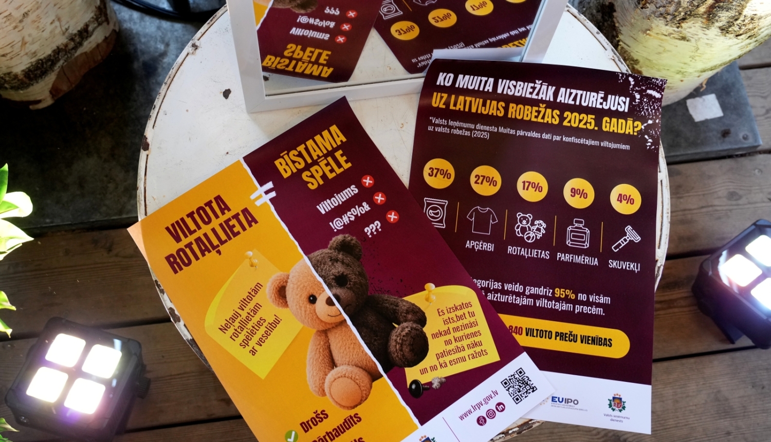 foto no kampaņas atklāšanas ar pasākuma plakātu un faktiem par konfiscētajiem viltojumiem