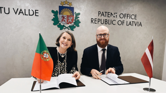 Patentu valdes direktors Agris Bataluaski sēžot pie galda, paraksta divpusēju sadarbības memorandu ar Portugāles Intelektuālā īpašuma iestādes direktori