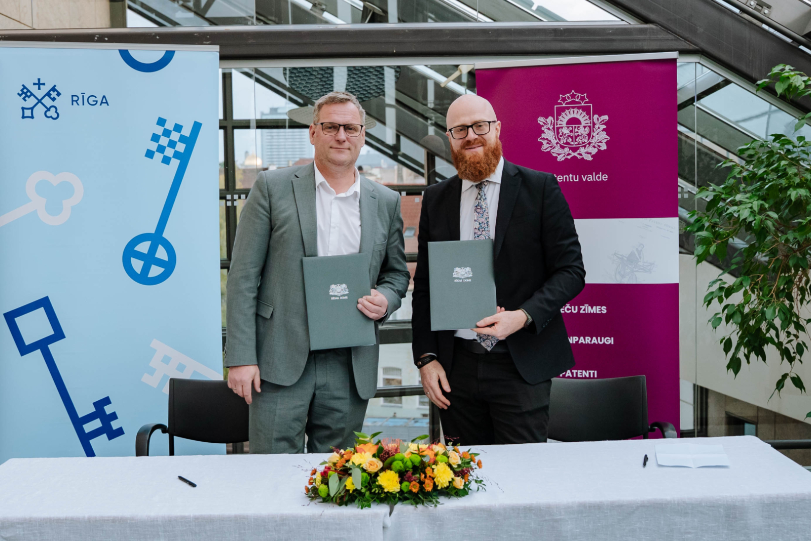 Patentu valdes direktors Agris Batalauskis un Rīgas domes mērs Viesturs Kleinbergs stāv  viens otram blakus un rokās tur dokumentus vākus ar parakstīto memorandu