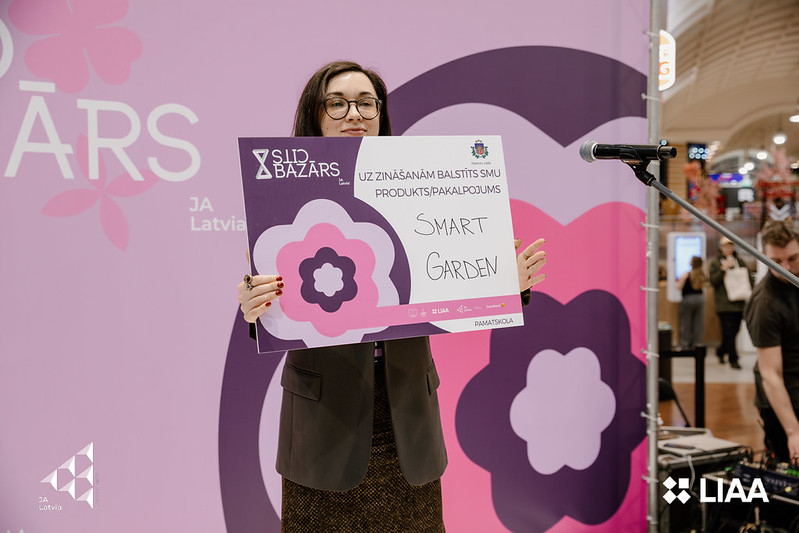 Bazārs pavasarī Attīstības un starptautiskās sadarbības departamenta direktore I. Grava uz skatuves pasniedzot balvu SMU "SmartGarden"