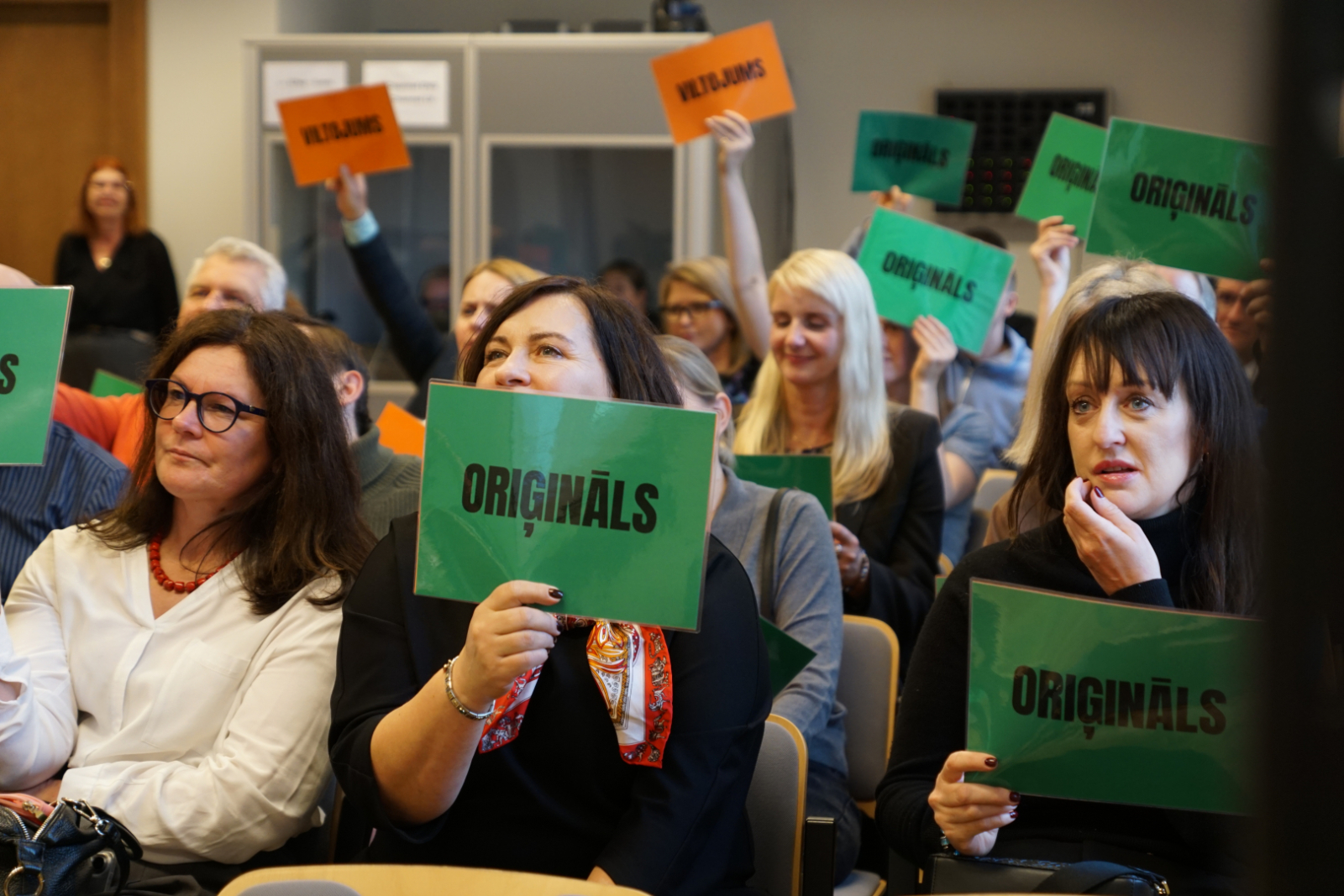 Muitas semināra 2025 dalībnieki turot rokā spēles kartītes 