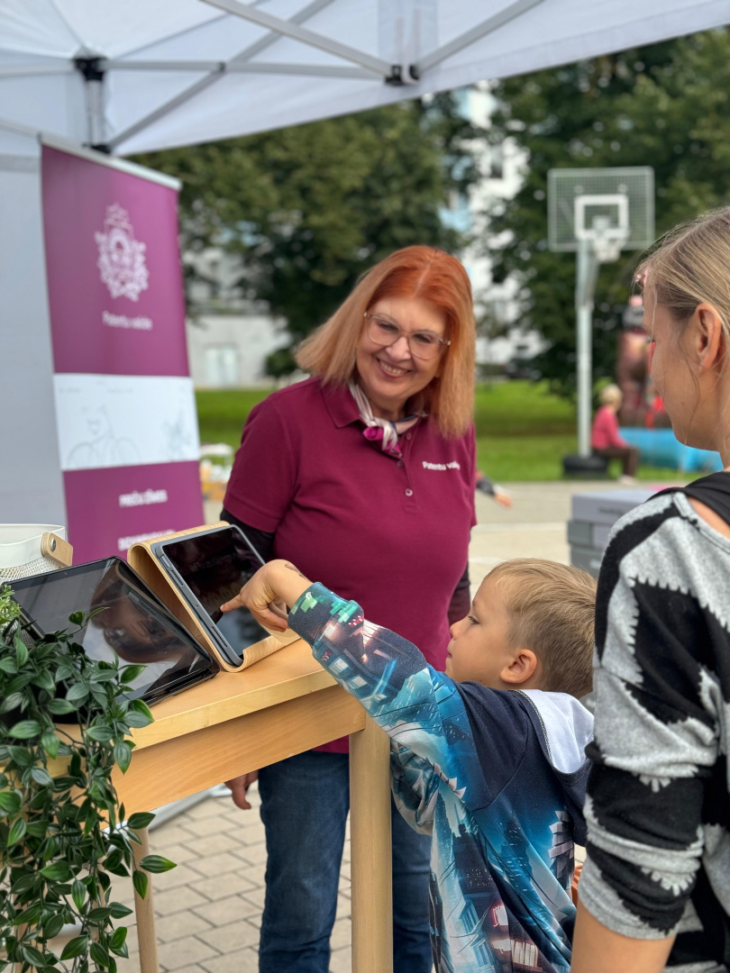 Apmeklētāji spēlējot preču zīmes minēšanas spēli planšetē