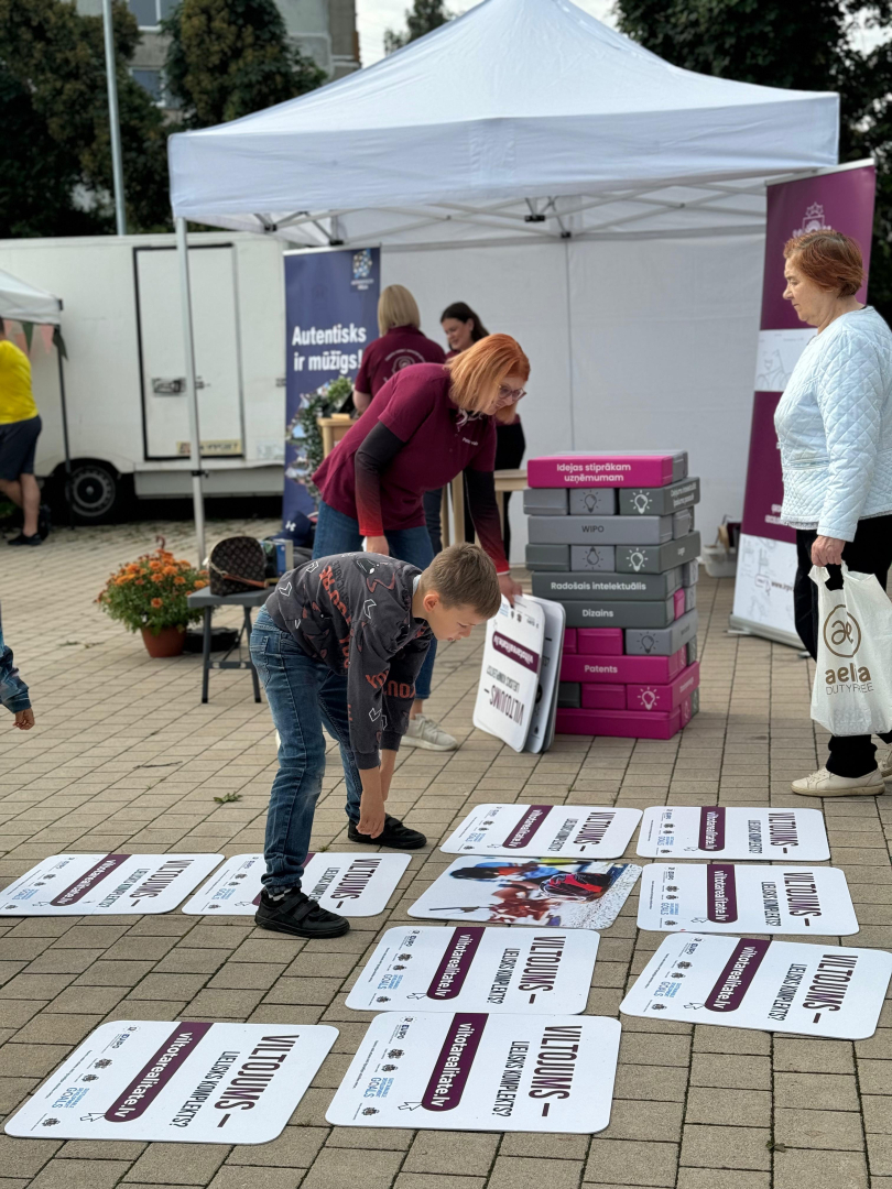 Apmeklētāji spēlējot lielformāta viltojumu atmiņas spēli