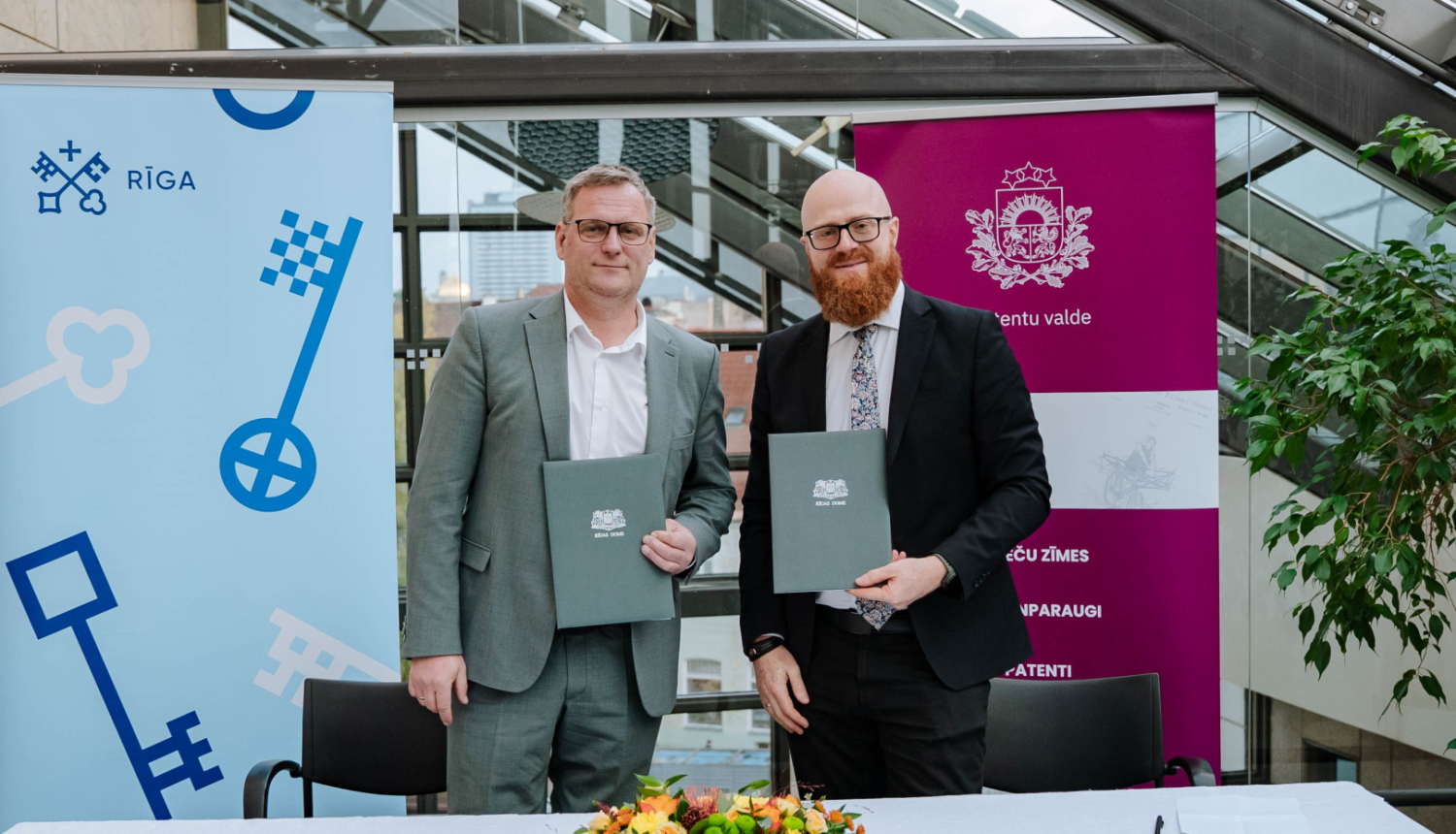 Patentu valdes direktors Agris Batalauskis un Rīgas domes mērs Viesturs Kleinbergs stāv  viens otram blakus un rokās tur dokumentus vākus ar parakstīto memorandu