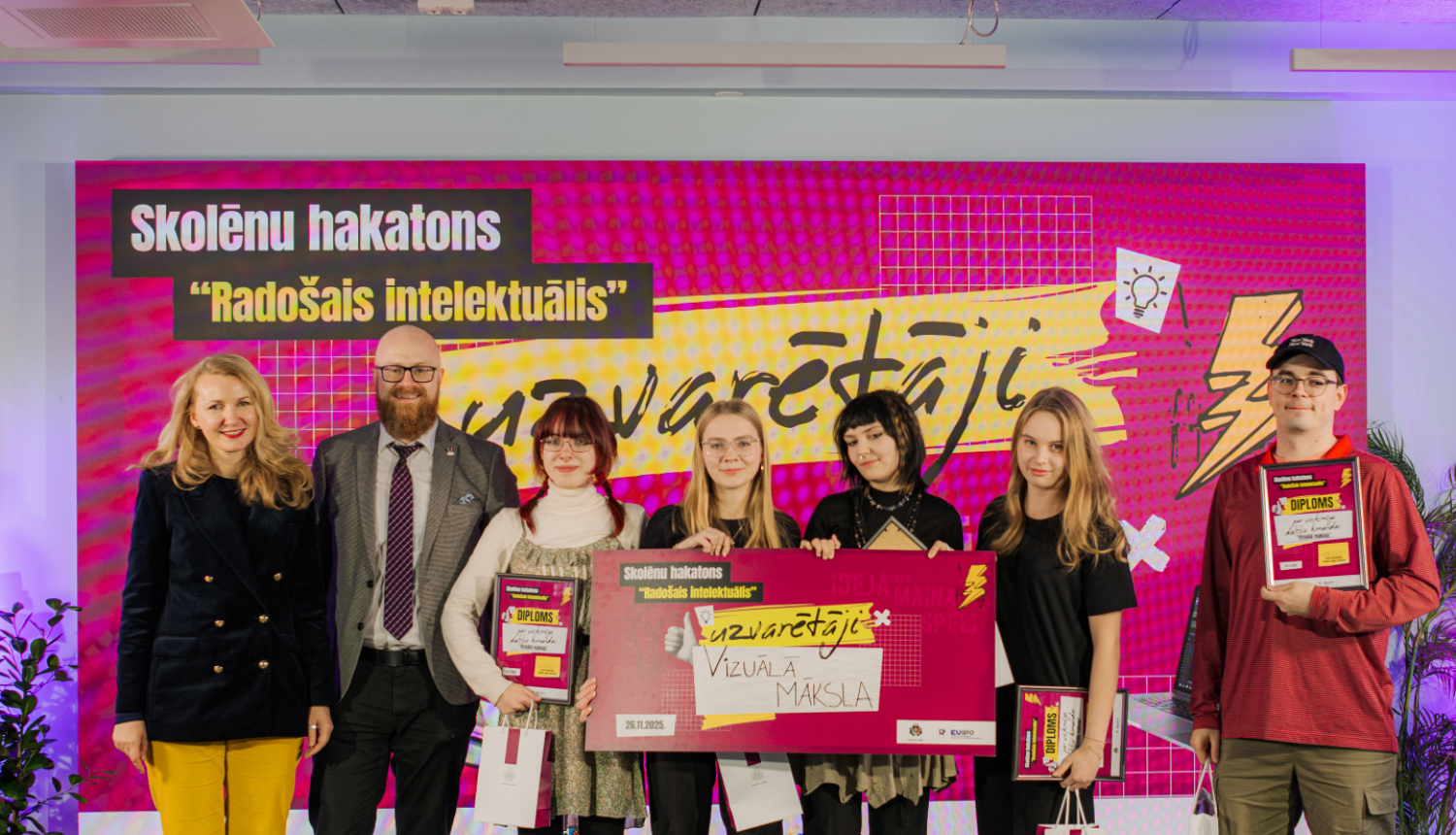 Skolēnu hakatona uzvartētāju kopbilde - četras meitenes un skolotājs kopā ar Patentu valdes direktoru un tieslietu ministri