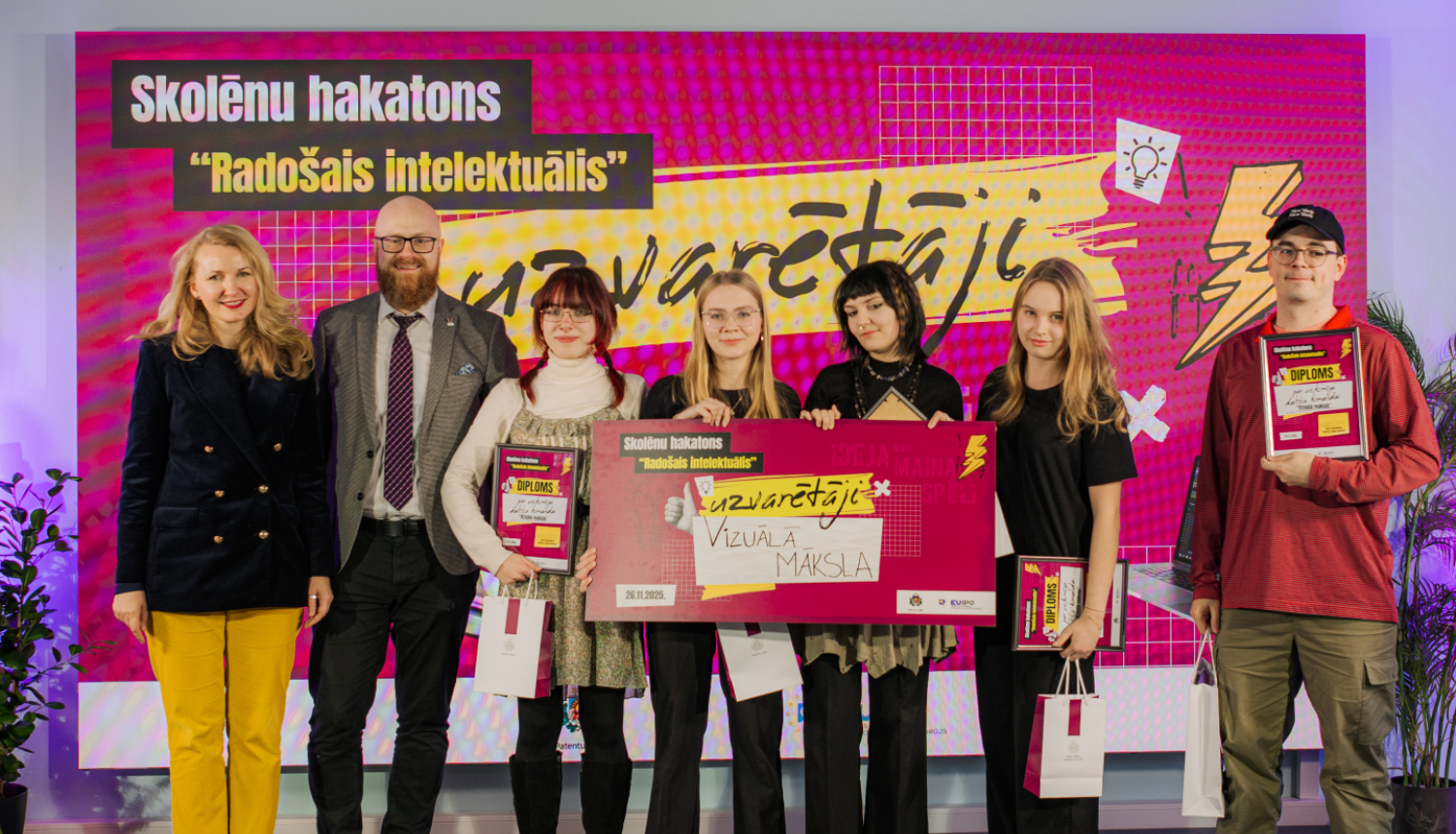 Skolēnu hakatona uzvartētāju kopbilde - četras meitenes un skolotājs kopā ar Patentu valdes direktoru un tieslietu ministri